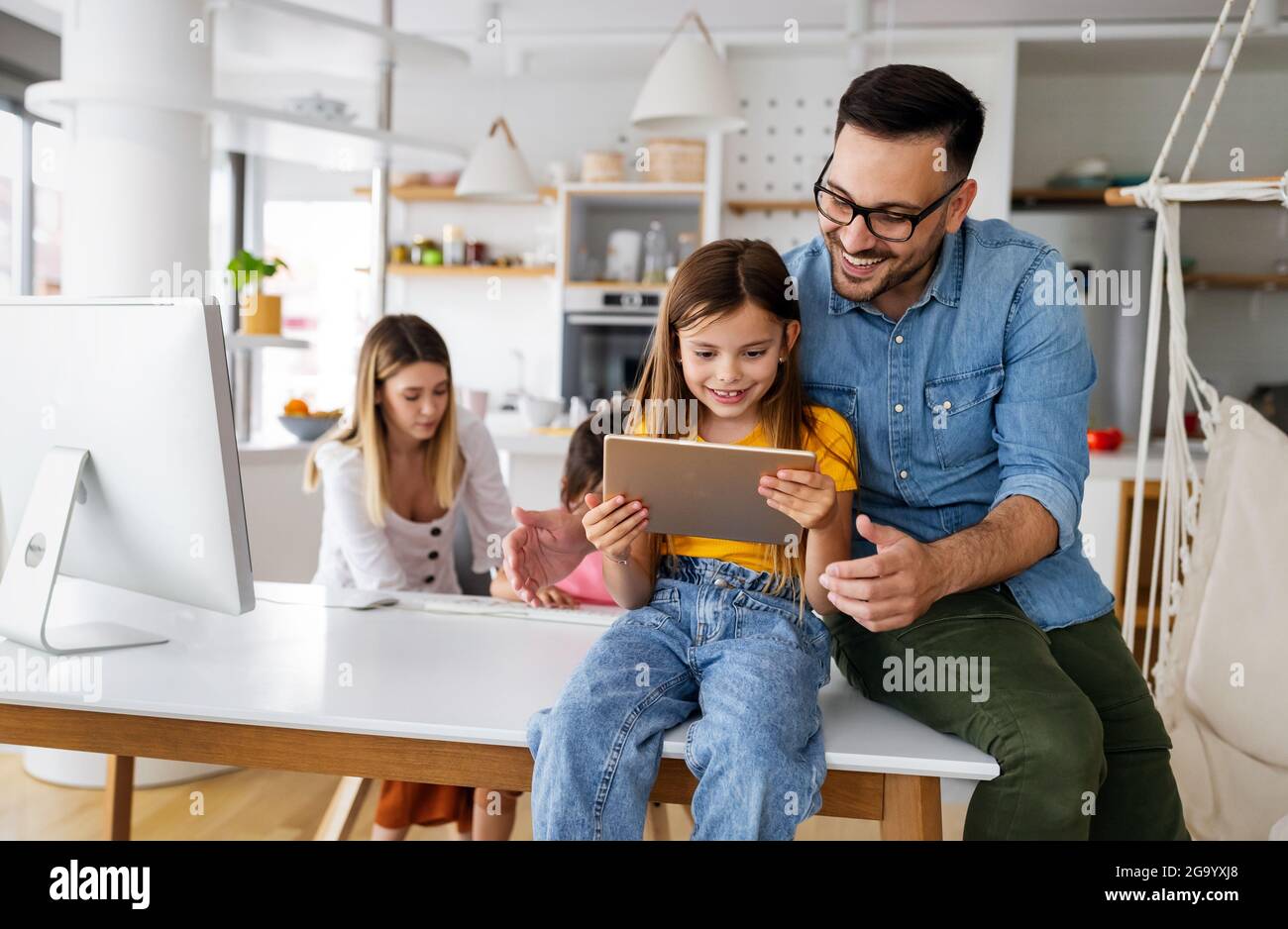 Parents helping to children studying online at home. Lockdown and online school, technology concept. Stock Photo