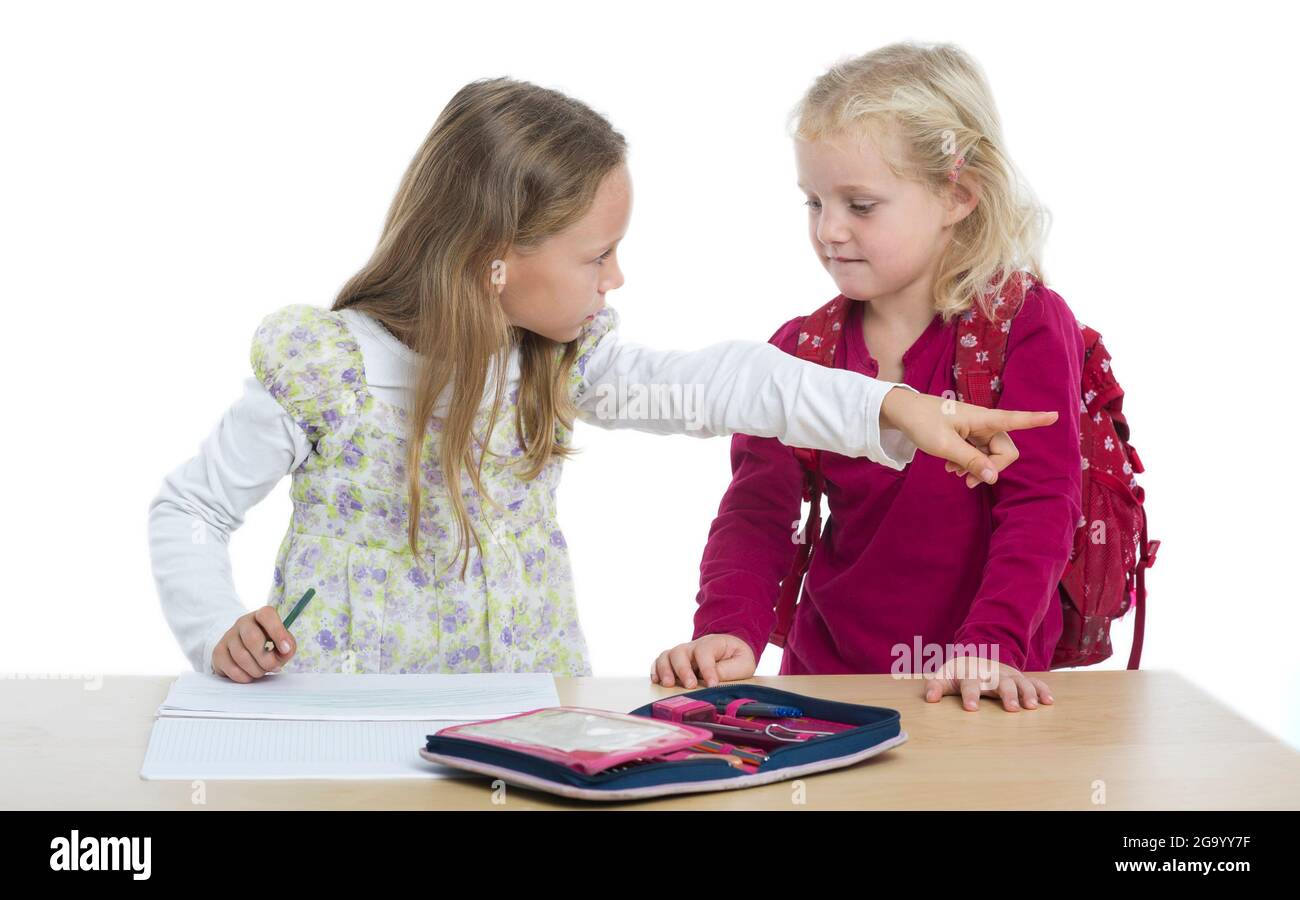 kindergartner with rucksack disturbing a sister while doing homework Stock Photo