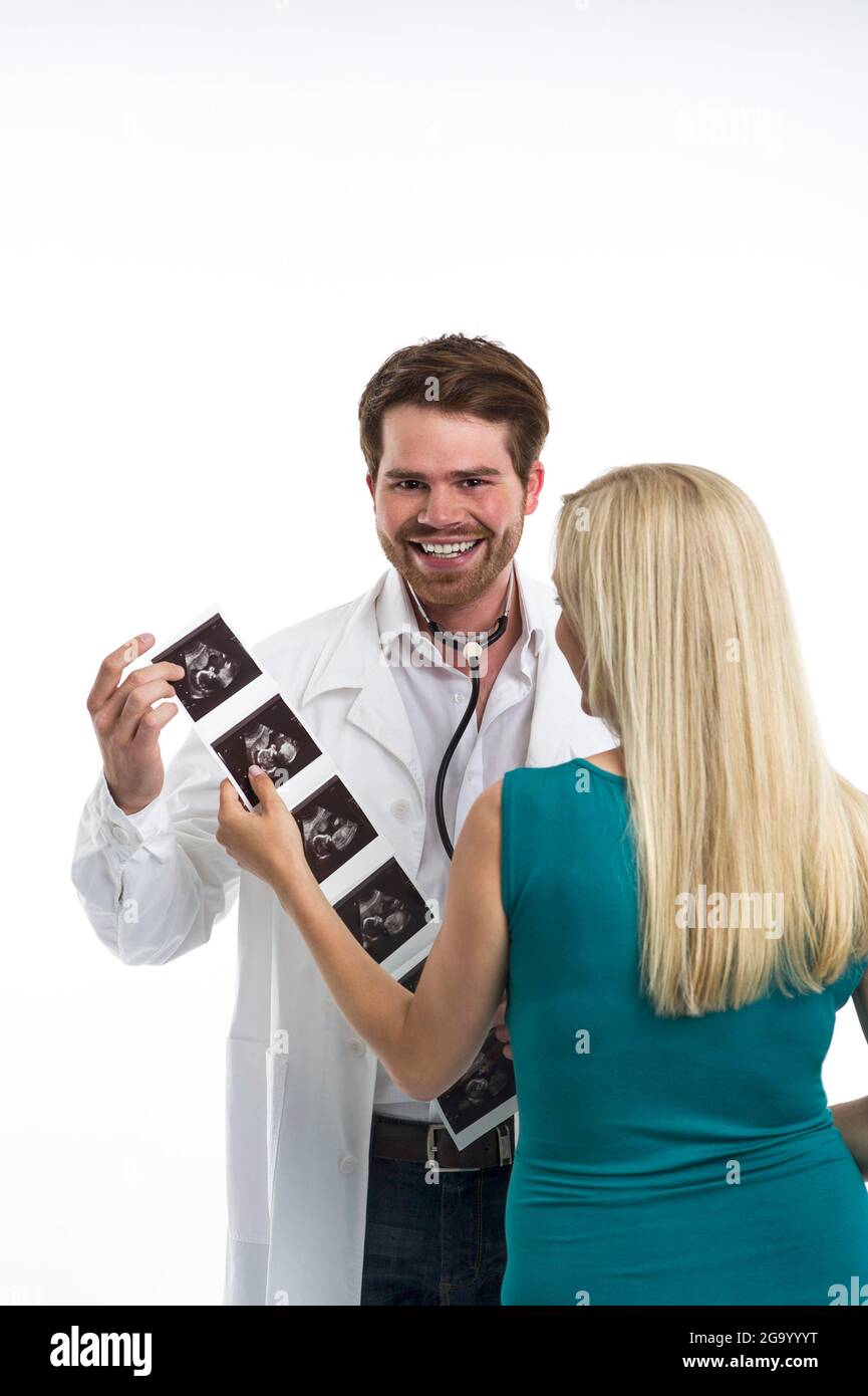 gynecologist happily handing over the ultrasound images with the unborn baby to a pregnant woman , Germany Stock Photo