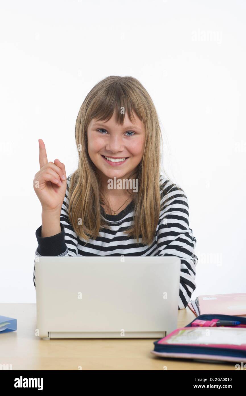 girl sitting with her index finger raised in front of a laptop, understanding Stock Photo