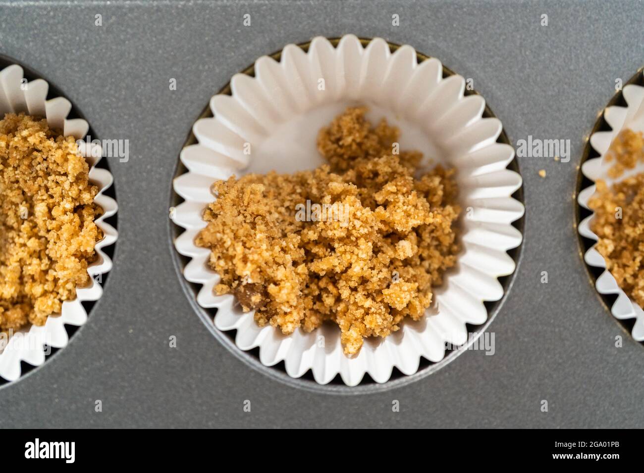 Filling cupcake liners with graham crackers to baking s mores cupcakes Stock Photo Alamy