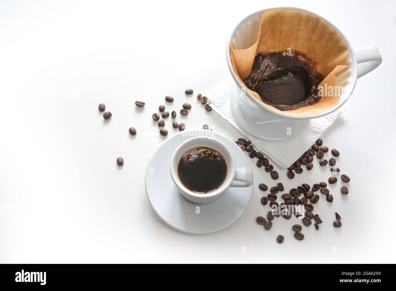 Coffee in a cup and ground coffee in a filter bag, drip brewed hot drink, light background fading to white with some beans, copy space, selected focus Stock Photo