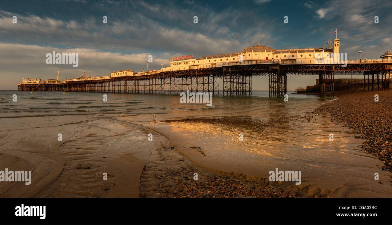 Brighton Pier in the morning sun with low tide sea and reflection
