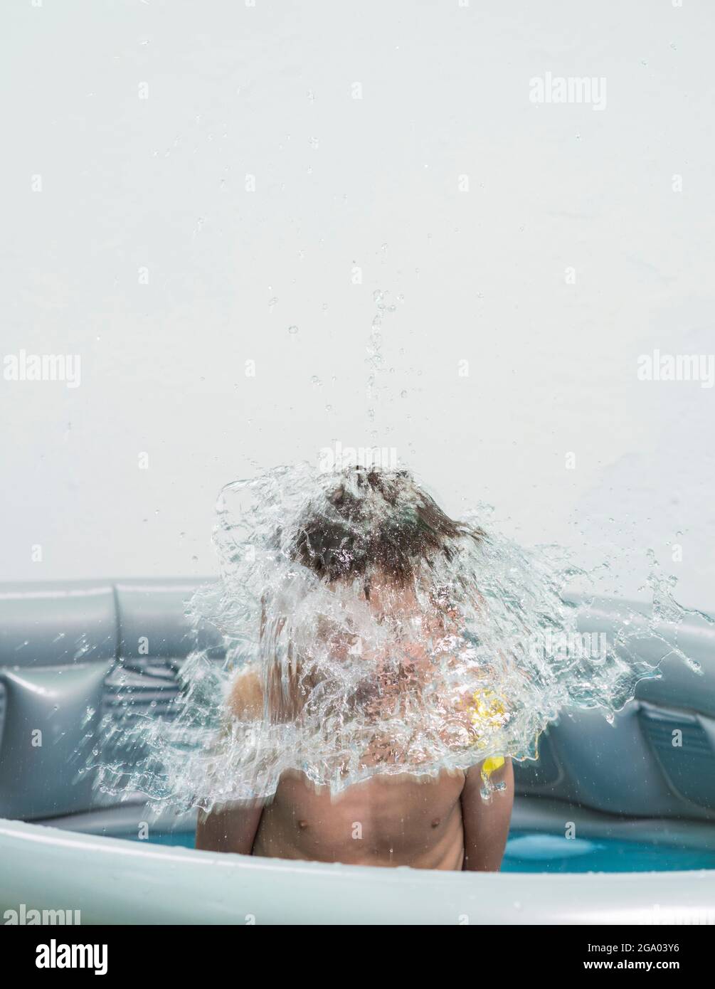 A water balloon exploding over a child's head. Water games are ideal to make the high summer temperatures more bearable. Stock Photo