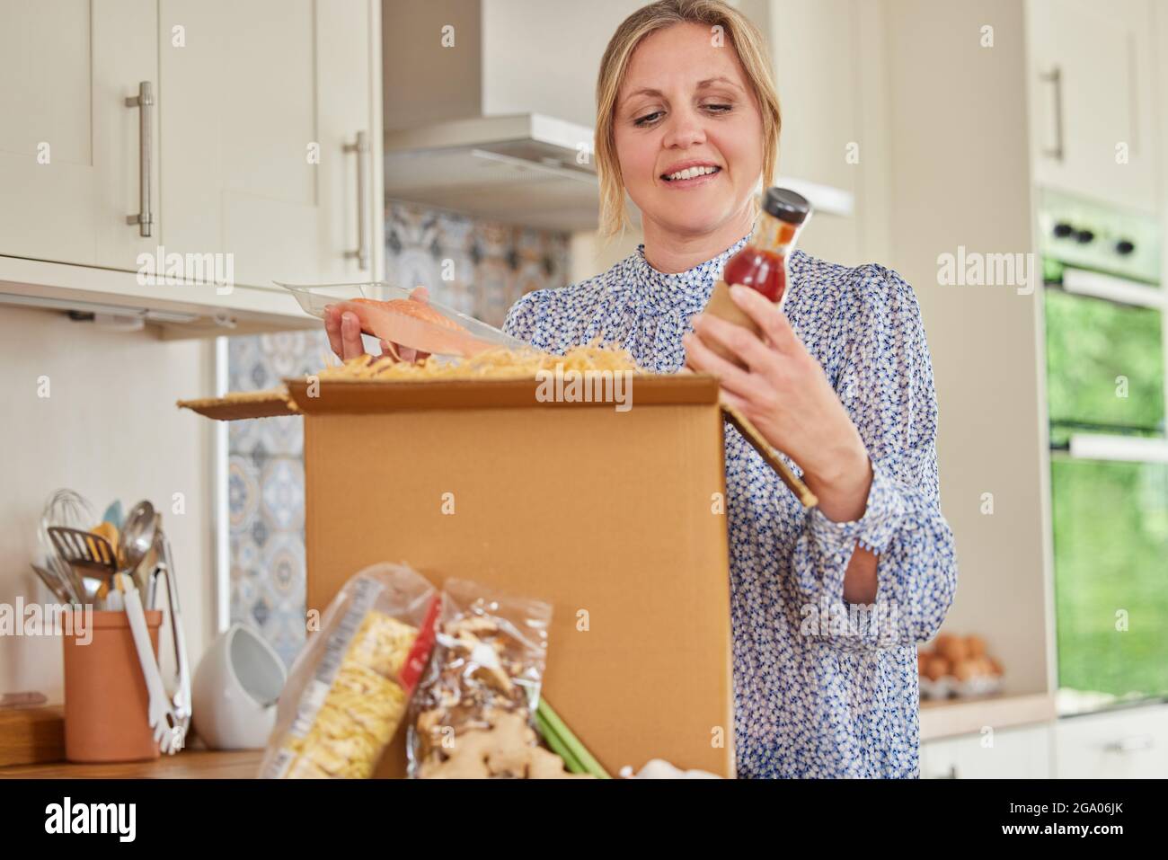 Woman Unpacking Online Meal Food Recipe Kit Delivered To Home Stock Photo