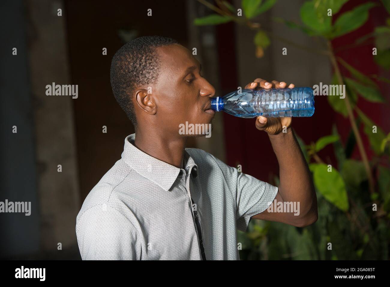 young man standing outdoors drinking water. Stock Photo