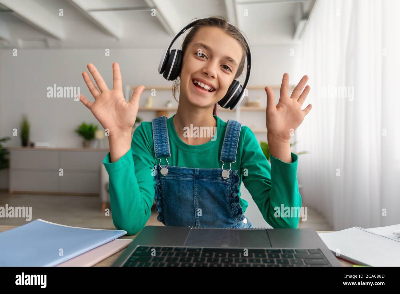 Girl sitting at desk, having video call wearing headphones Stock Photo