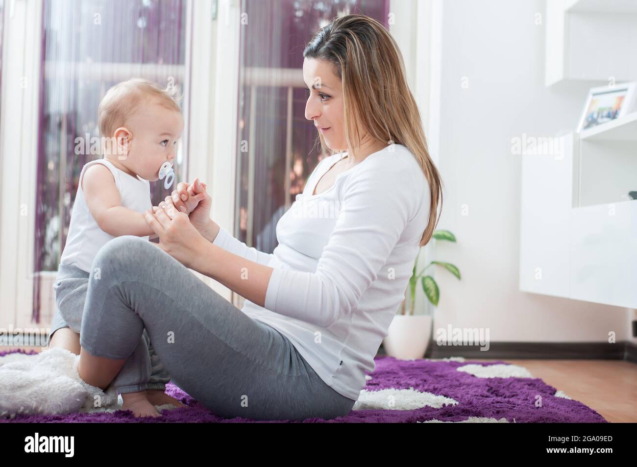 Happy mother sitting on the floor and playing with her baby boy Stock ...