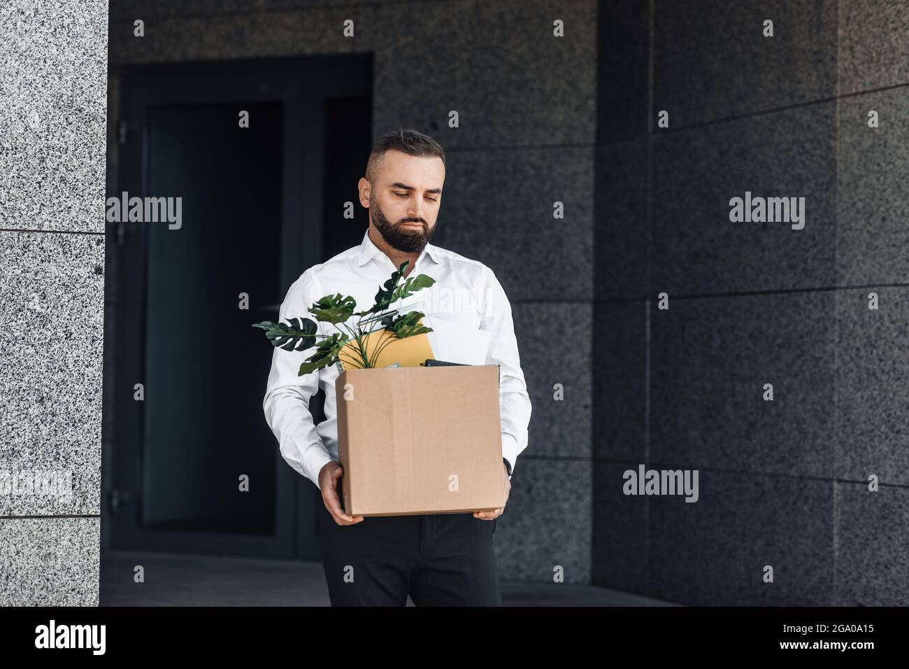 Jobless male worker moving out office with box full of personal belongings, lost job and left without money, copy space Stock Photo