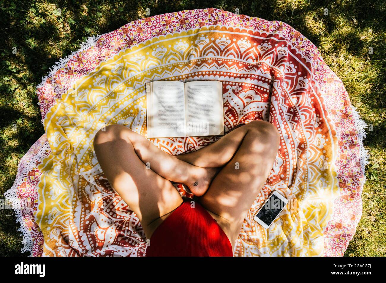 woman reading on a towel in the garden with swimsuit under a tree Stock Photo