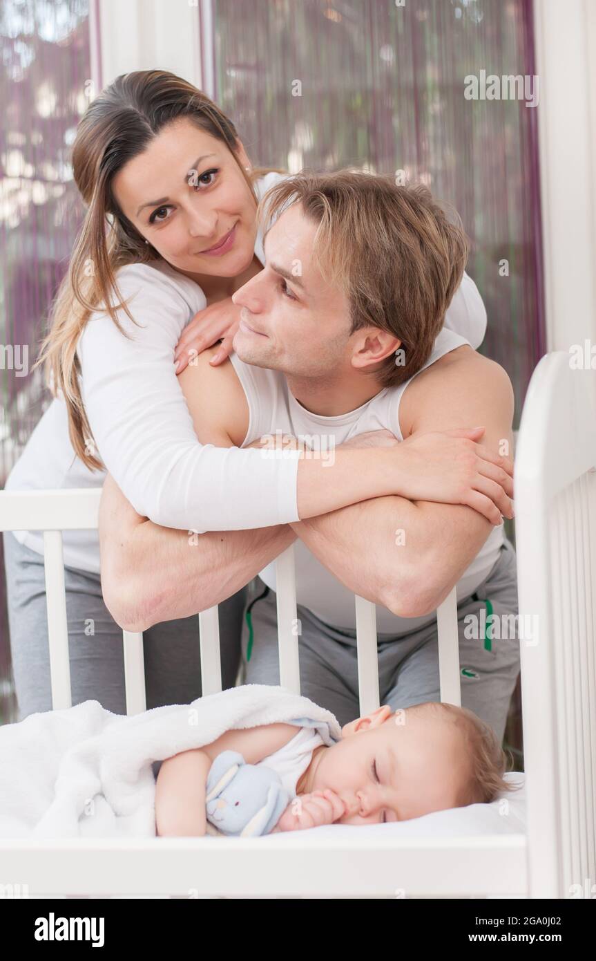 Happy parents standing beside the baby's bed. Happiness and pride. Stock Photo