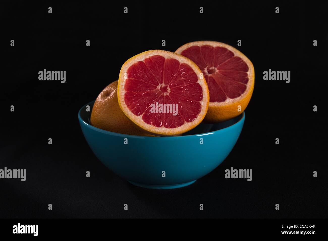 red grapefruit in blue bowl on black background Stock Photo