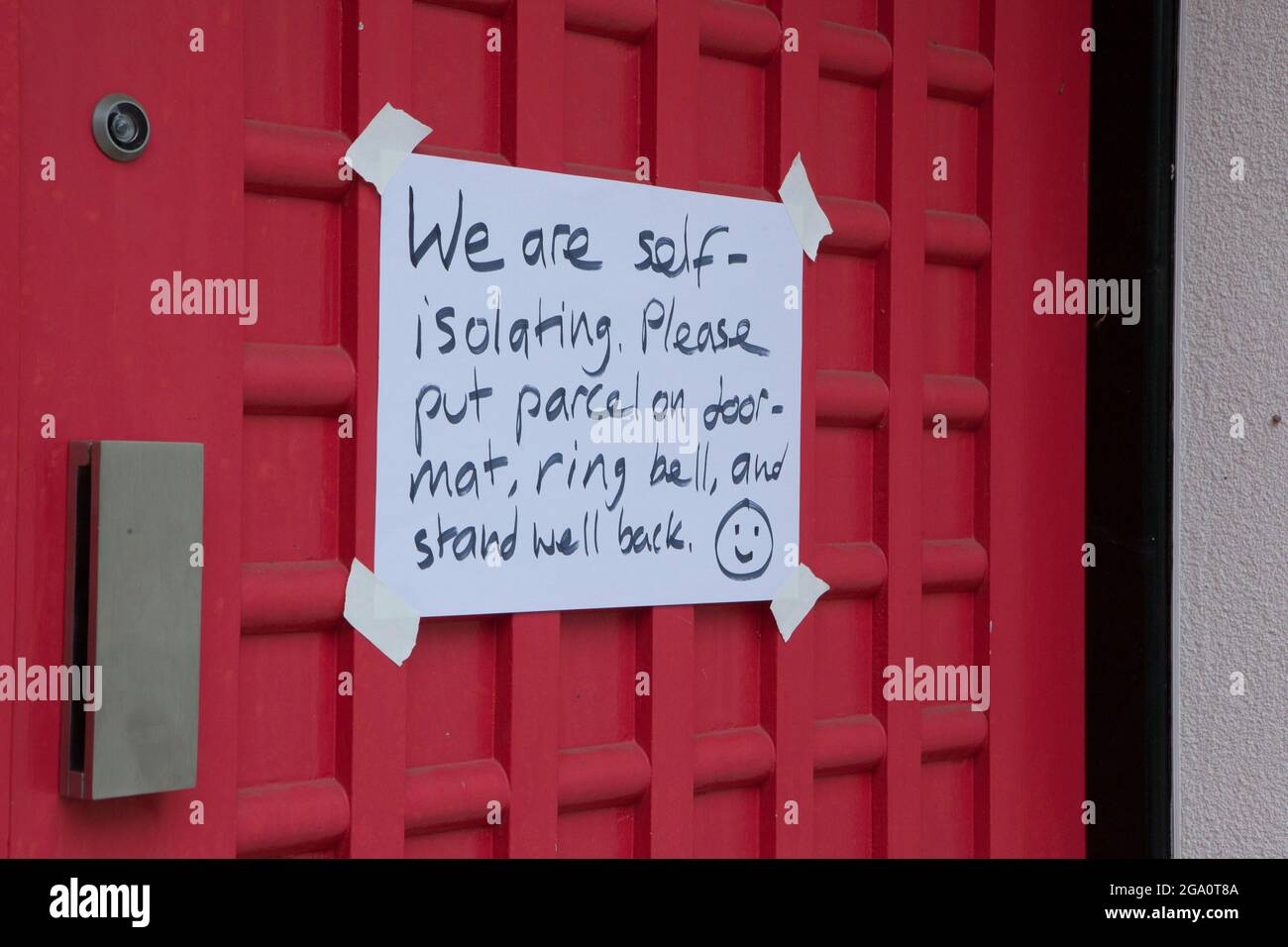 London, UK, 28 July 2021: on the front door of a house in Clapham a hand-written sign warns delievery drivers that the residents are self-isolating. With the pingdemic causing many people to self-isolate, the country is reliant as much as ever on delivery drivers. Seven days of falling numbers of new cases have given some hope that the third wave isn't as bad as some might have feared. Anna Watson/Alamy Live News Stock Photo
