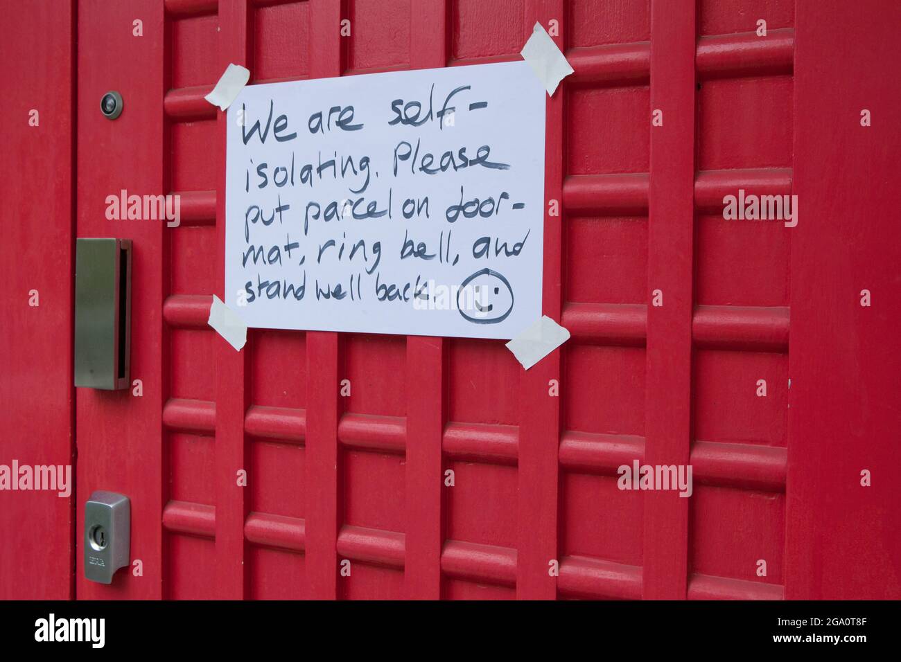 London, UK, 28 July 2021: on the front door of a house in Clapham a hand-written sign warns delievery drivers that the residents are self-isolating. With the pingdemic causing many people to self-isolate, the country is reliant as much as ever on delivery drivers. Seven days of falling numbers of new cases have given some hope that the third wave isn't as bad as some might have feared. Anna Watson/Alamy Live News Stock Photo