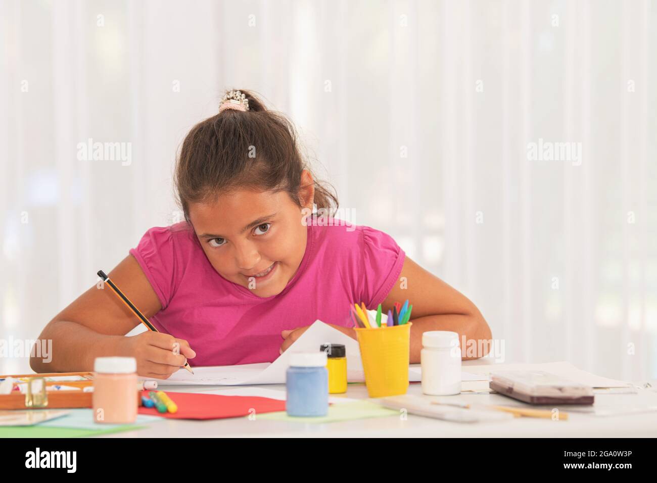 Little girl drawing and looking at camera in class Stock Photo - Alamy