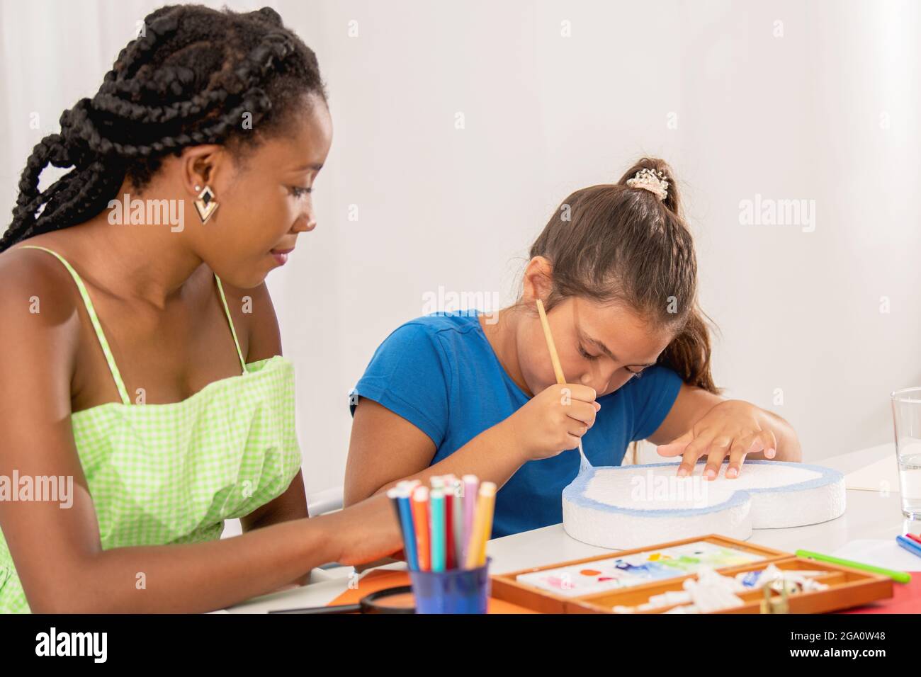 Girl painting with her teacher in art class Stock Photo - Alamy