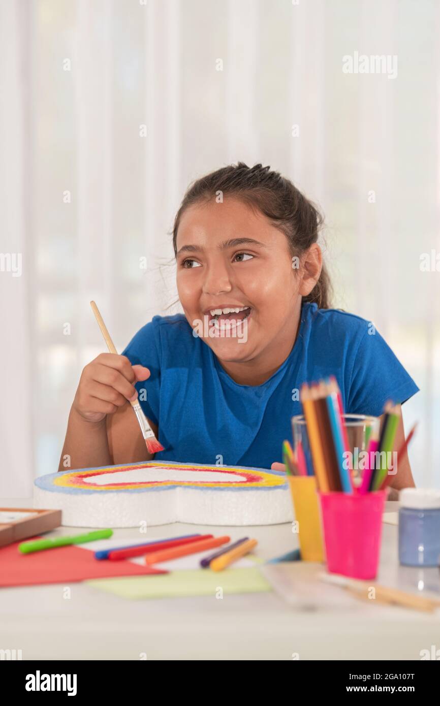 View of a joyful latina girl painting in art class Stock Photo - Alamy