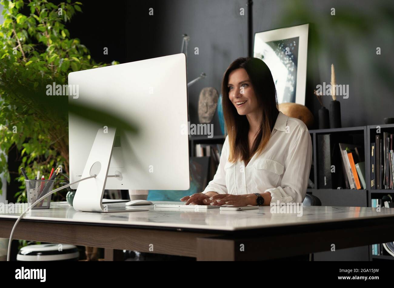 Attractive young woman working at office, using contemporary desktop ...
