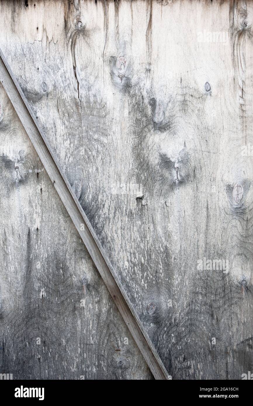 Old worn wooden door. Grunge door surface with rifts. Abstract background. Diagonal line in the middle. Stock Photo