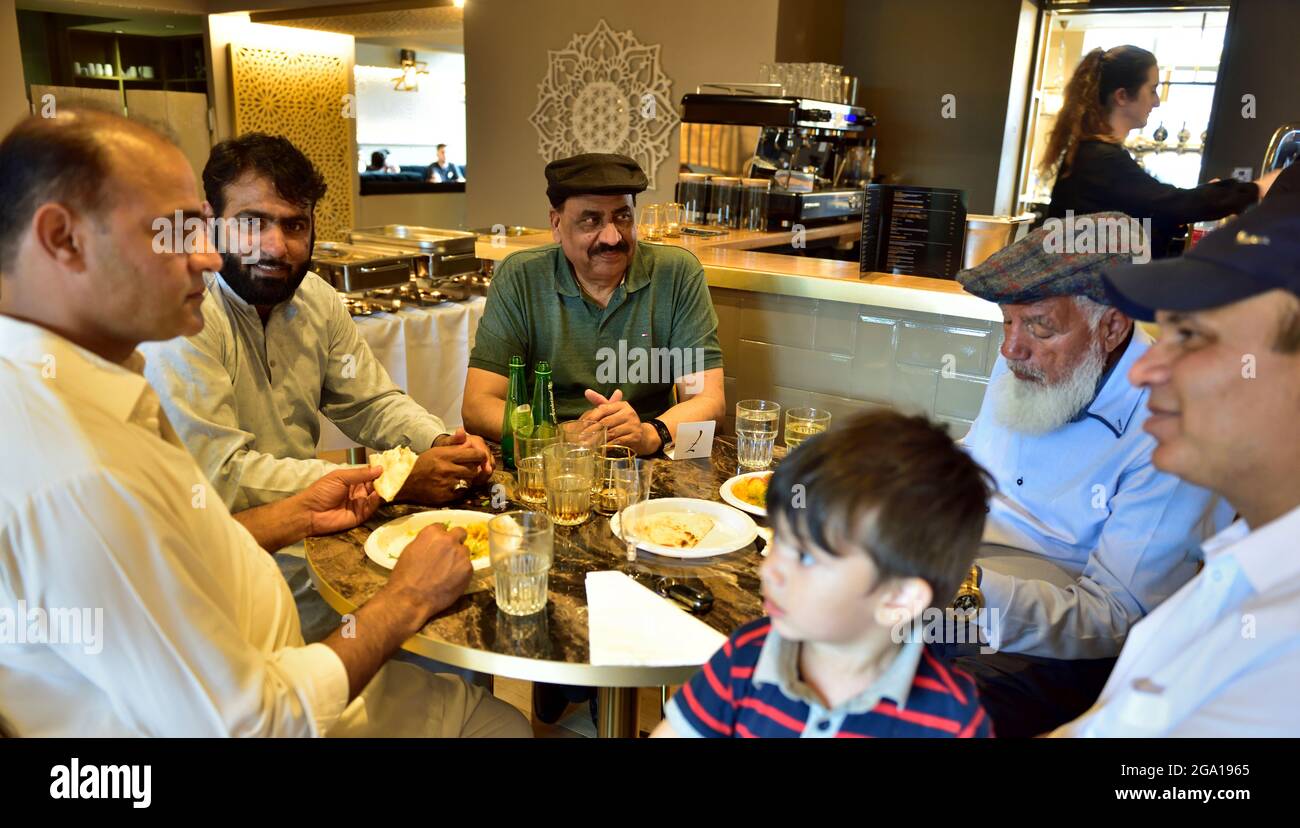 Inside Indian restaurant men eating at table Stock Photo