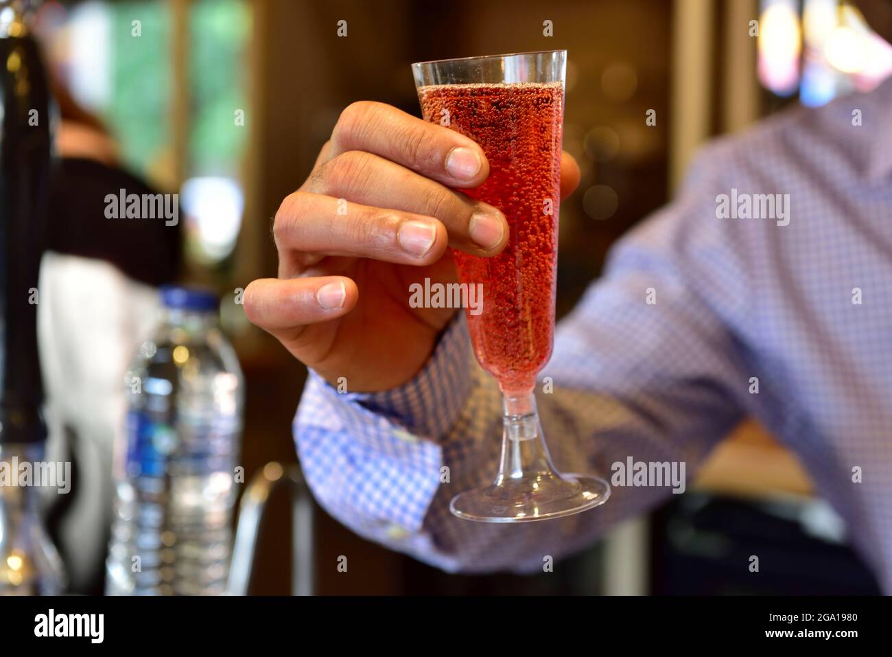 Man's hand holding up a glass of bubbly Champaign or wine Stock Photo