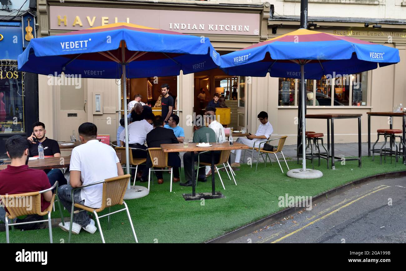 Tables and chairs with customers of restaurant, bar, pub out on pavement for food and drinks, Bristol, UK Stock Photo