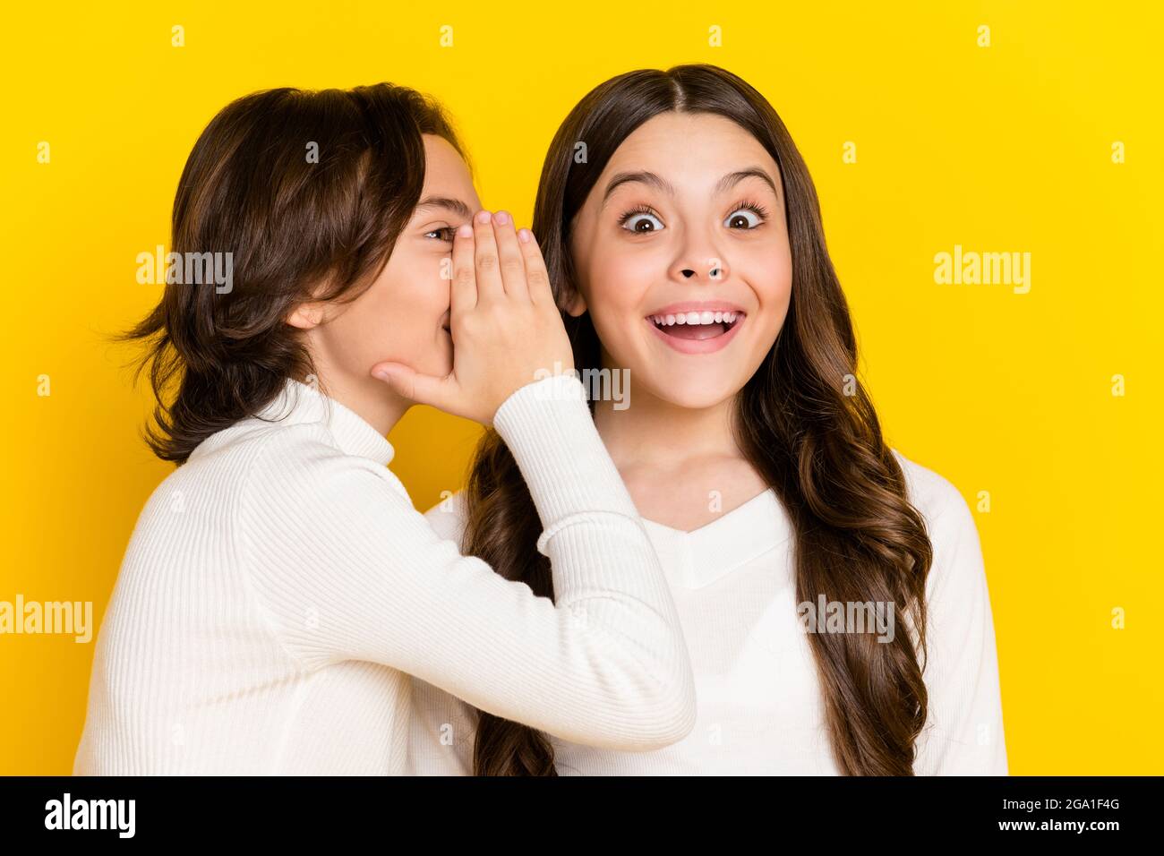 Photo portrait of little boy whispering amazed cheerful girl secret isolated on vibrant yellow color background Stock Photo