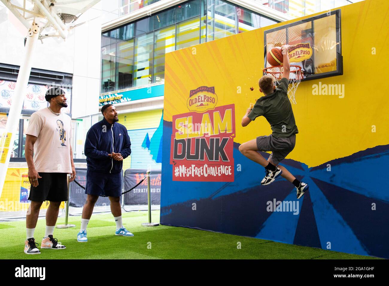 EDITORIAL USE ONLY (Left-right) Ashley and Jordan Banjo watch as Gabriel Gibbon, age 13 takes part in the Old El Paso Slam Dunk #MessFreeChallenge at Westfield, London, to celebrate the launch of