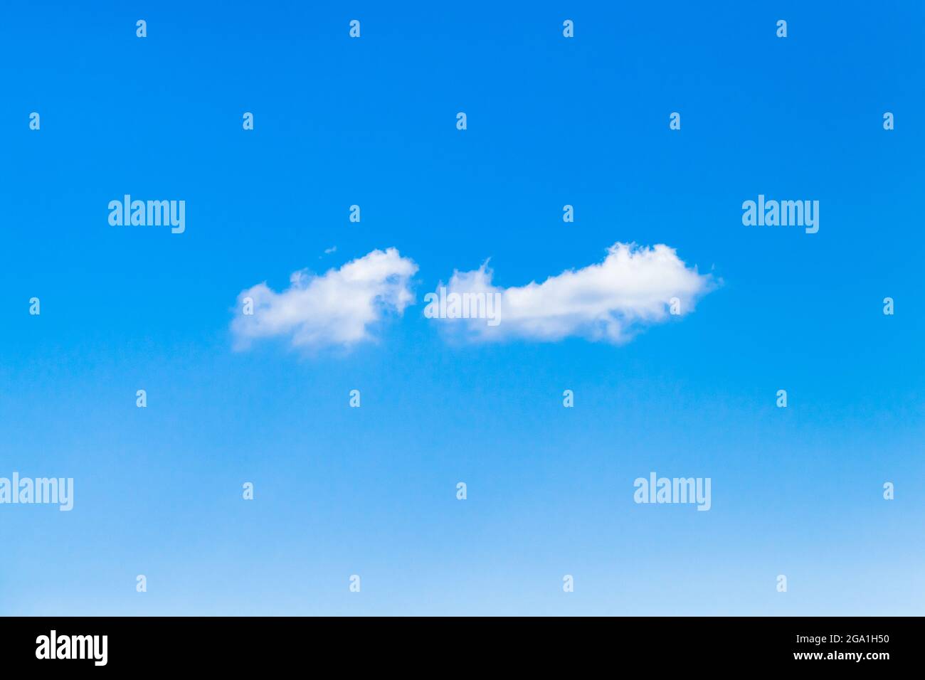 Two small white clouds fly in clear blue sky on a daytime, natural background photo Stock Photo