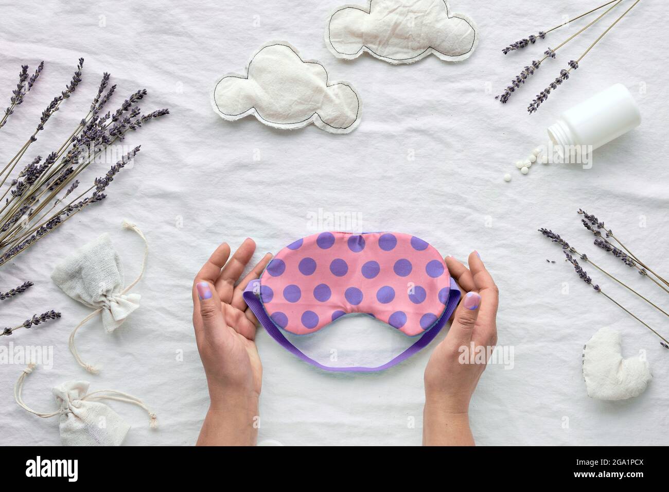 Healthy night sleep flat lay. Pink sleep mask with polka dots in hands