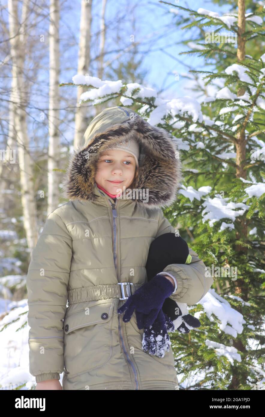 Little girl walking in snow-covered winter forest. Child exploring nature. Stock Photo