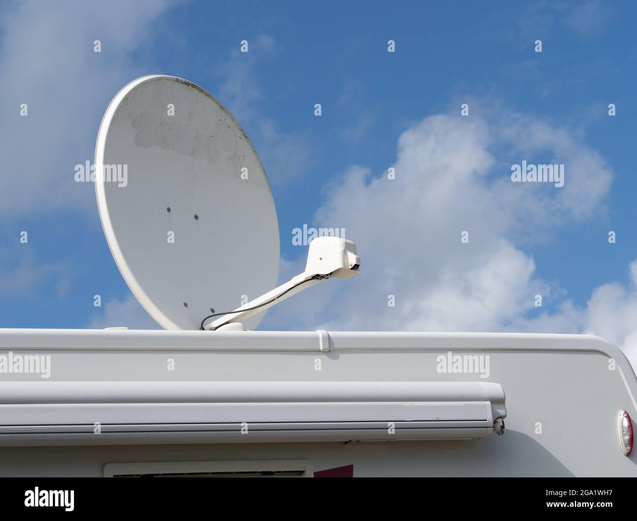 A large roof top satellite dish on top of a motorhome recreational vehicle against a blue sunny sky Stock Photo
