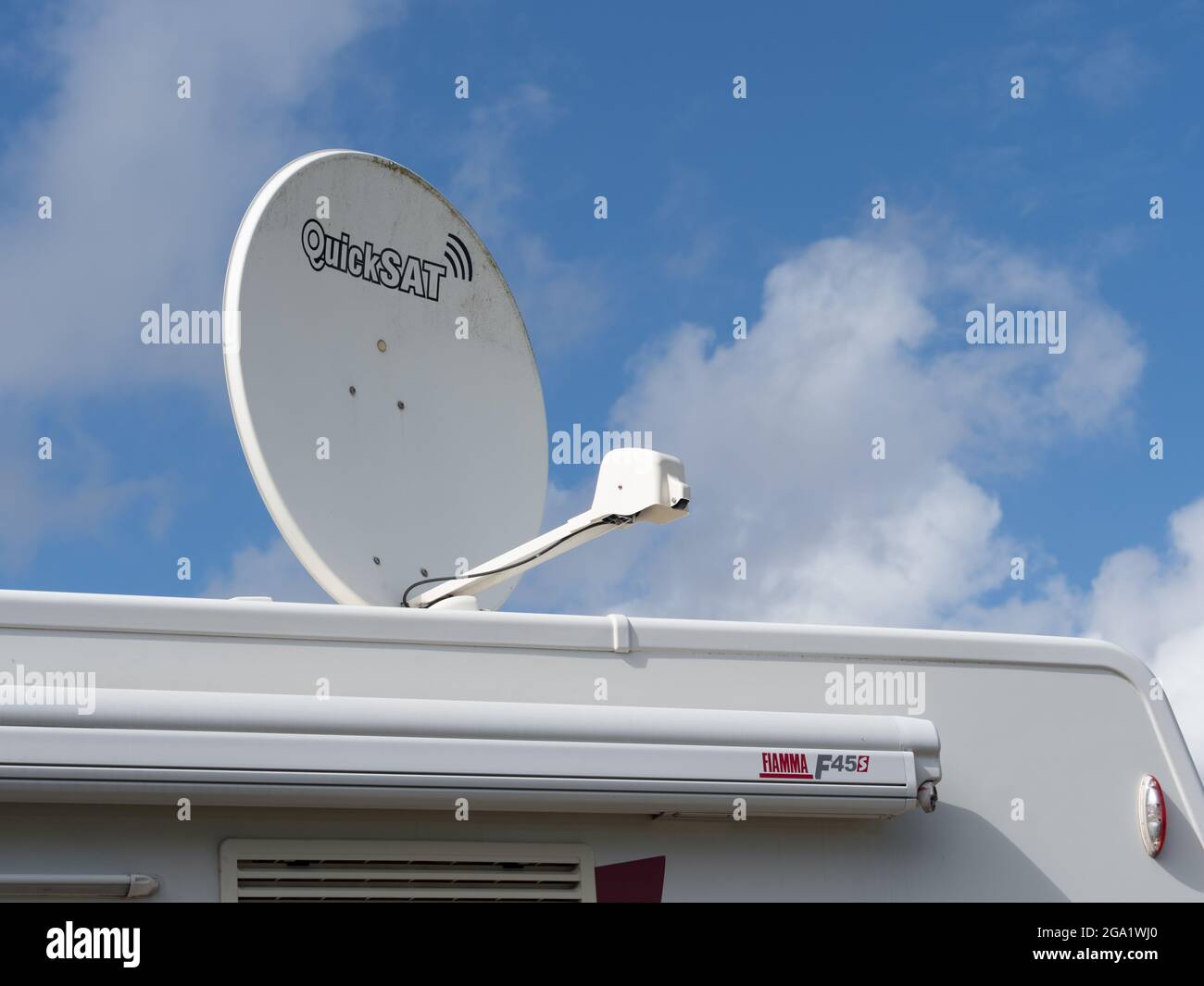 A large roof top satellite dish made by Quicksat on top of a motorhome recreational vehicle against a blue sunny sky Stock Photo