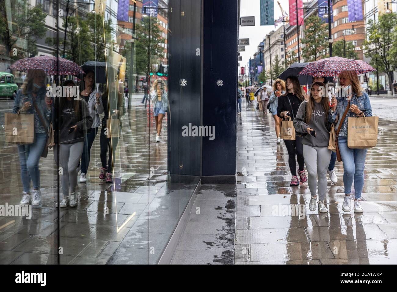Tourists out shopping during one of the wettest July's ever recorded with the high amounts of rain showers in history, Oxford Street, London, UK Stock Photo