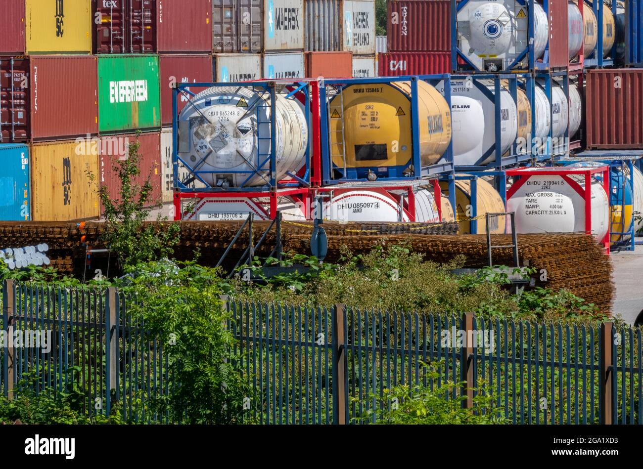 shipping containers and fuel transport tanks at a storage depot near manchester. multi-coloured storage containers and tanker in protective frames. Stock Photo