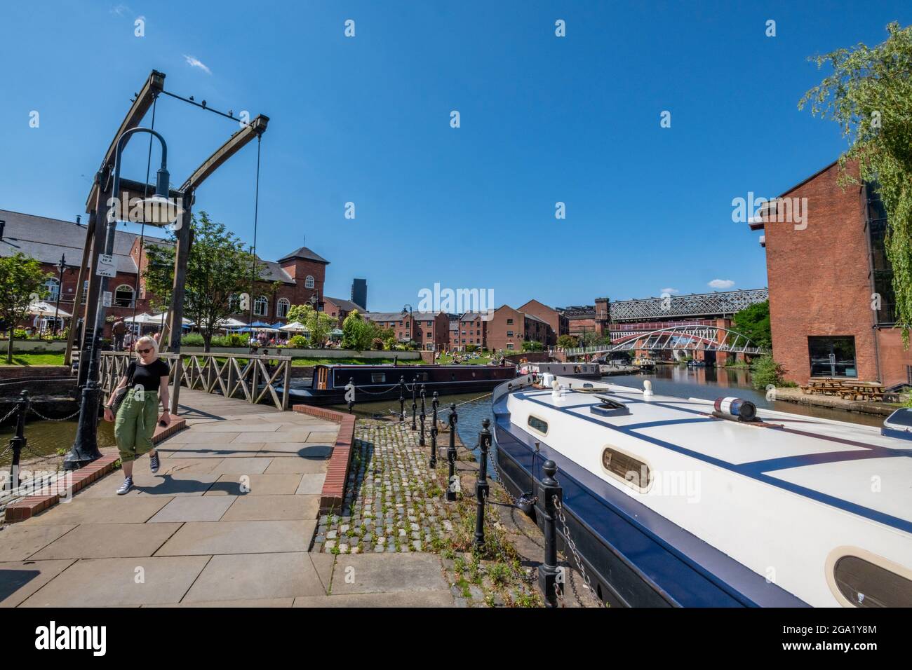 victorian engineering lifting bridge on the bridgewater canal in manchester city centre next to the canal with a barge or narrowboat houseboat. Stock Photo