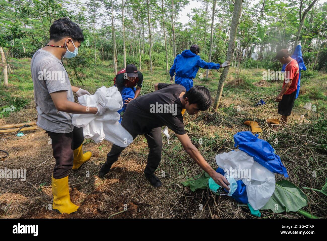 Funeral workers burn personal protective equipment after burial a 