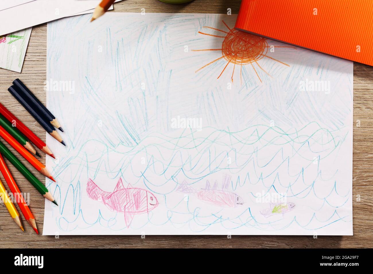 Kids drawing on white sheet of paper with crayons and markers on wooden  table, closeup Stock Photo - Alamy