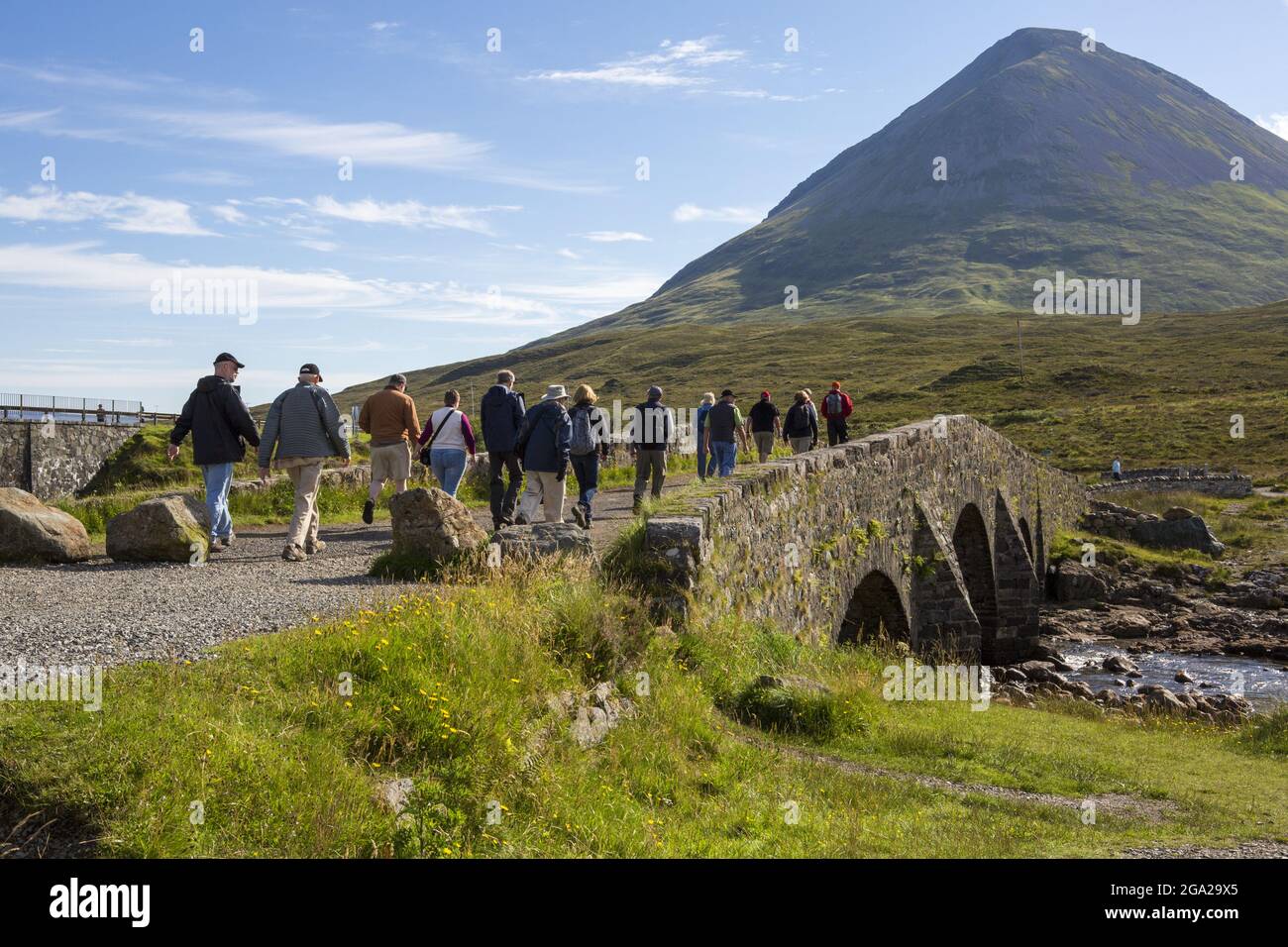 Hikers cross a bridge leading to a trail through the Cuillin Mountains near Sligachan, Isle of Skye, Scotland. Stock Photo
