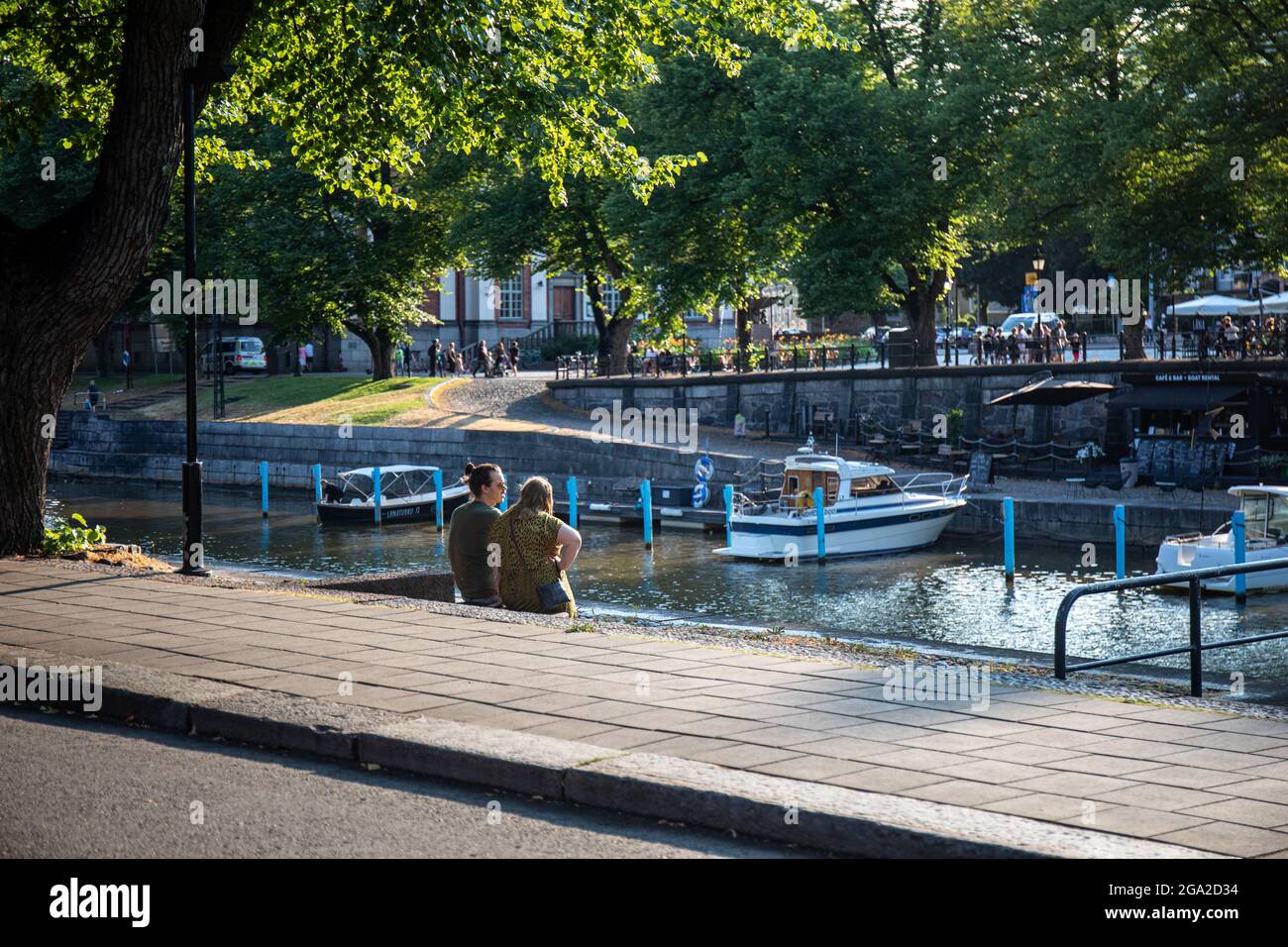 Young couple sitting on the bank of River Aura in the evening sun in Turku, Finland Stock Photo