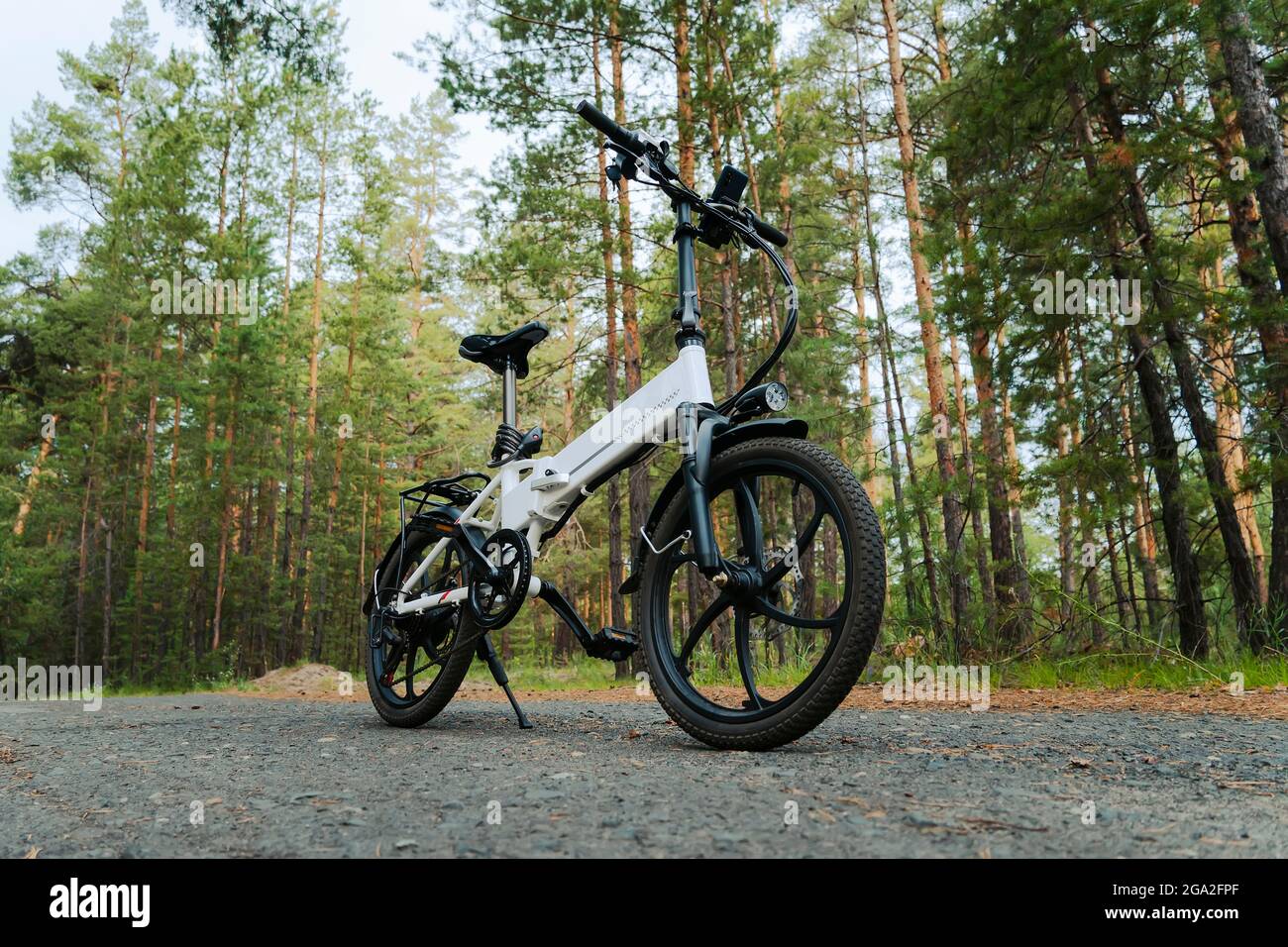 Eco friendly mode of transport. bicycle with an electric motor. An electric bike of white color on the background of a green forest. Stock Photo