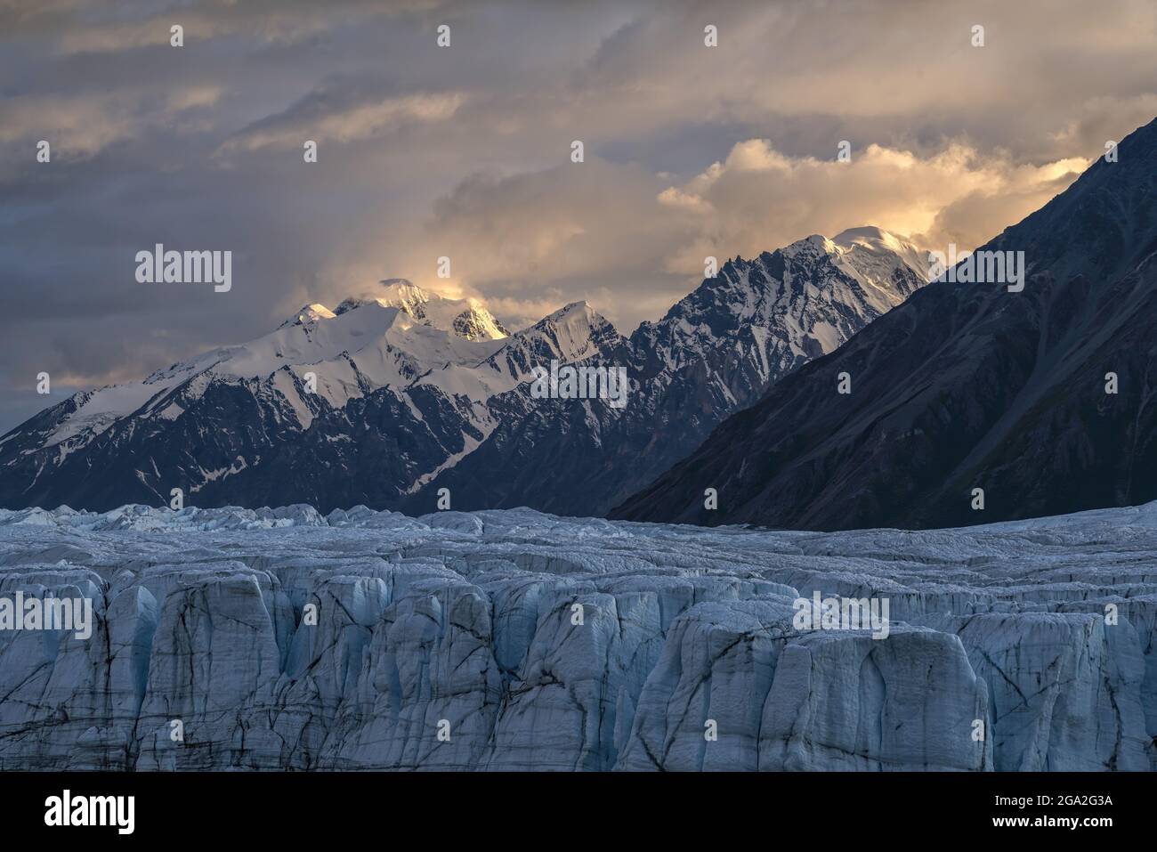 The vast Donjek Glacier in Kluane National Park with the sunset lighting up the clouds over the snowcapped mountaintops creating a stunning image, ... Stock Photo