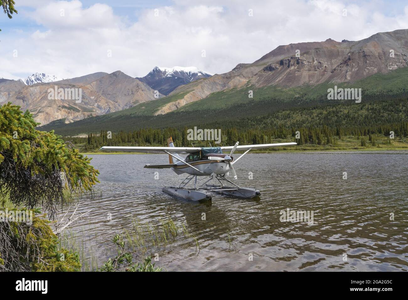 Floatplane on the water resting near the shore of a lake with mountains in the background; Kluane National Park and Reserve, Yukon, Canada Stock Photo