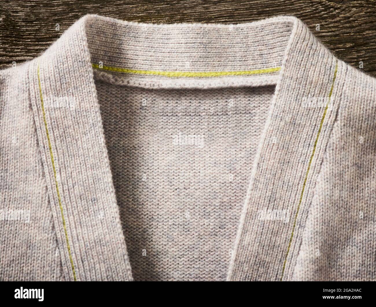 Collar and neckline of a grey cardigan sweater with yellow stitching; Studio Stock Photo