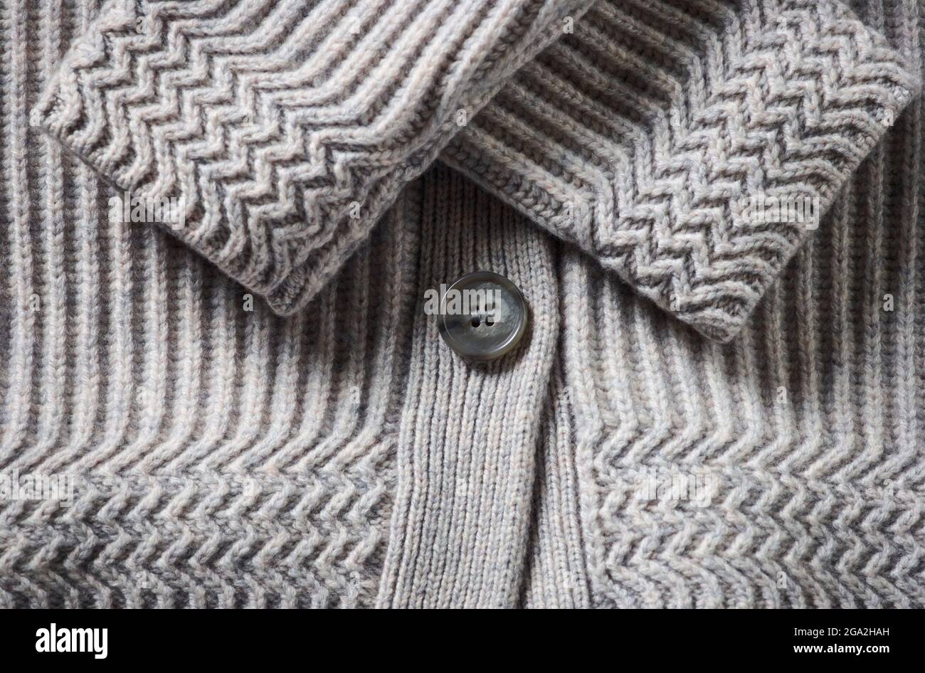Extreme close-up of the cuffs and button on a grey knit sweater; Studio Stock Photo