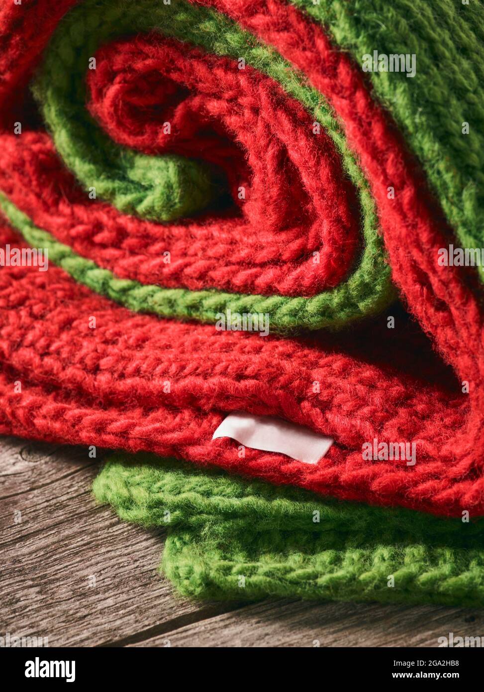 Close-up of a red and green knitted garments folded together and laying on a wooden table; Studio Stock Photo