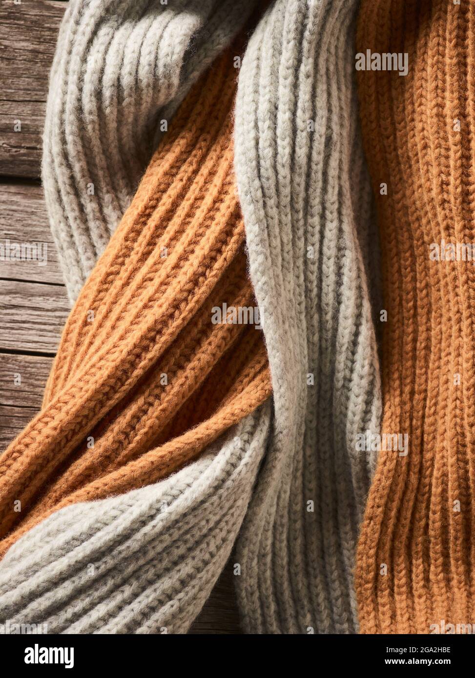Close-up of neutral coloured knit garments laying on a wooden table; Studio Stock Photo