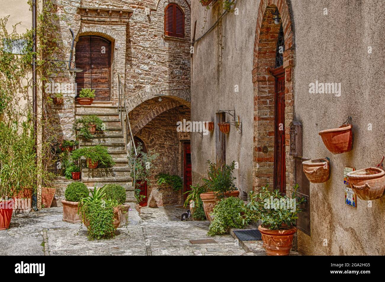 Exterior of an old, stone building with a staircase and three entrances to separate apartments with terracotta flower pots on the terrace as well a... Stock Photo