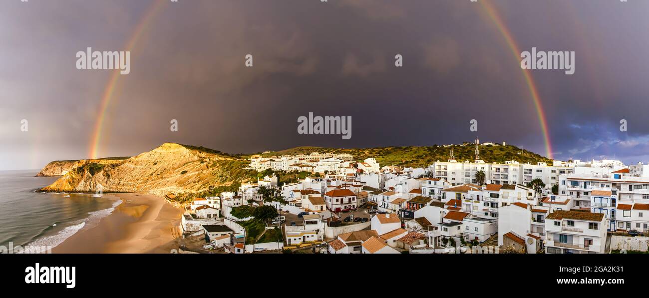 Rainbow arching over the traditional fishing village of Burgau under a stormy sky in the municipality of Vila do Bispo in the Western Region of Alg... Stock Photo