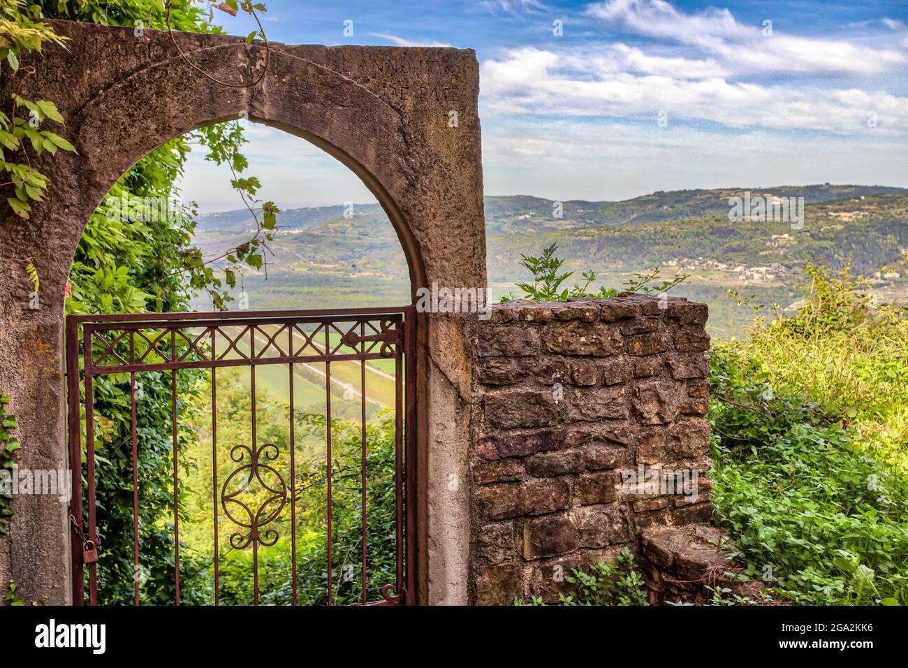 View of the countryside from the stone ruins with an iron gate in the historic village of Motovun, overlooking the hills of Istria; Motovun, Croatia Stock Photo